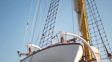 Yüksek direkli ve sarı kapaklı büyük bir yelkenli. Yelken açıldı, gökyüzü açık. Yüksek kalite
