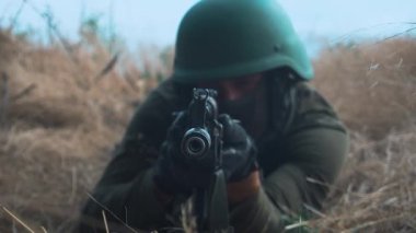Elinde makineli tüfek olan bir asker siperde oturur. Yüksek kaliteli FullHD görüntüler
