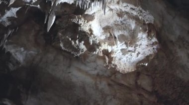 Tavandan sarkıtlar sarkan bir mağara. Mağara karanlık ve sarkıtlar aydınlık..