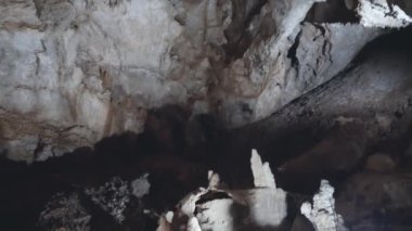 Tavandan sarkıtlar sarkan bir mağara. Mağara karanlık ve sarkıtlar aydınlık..