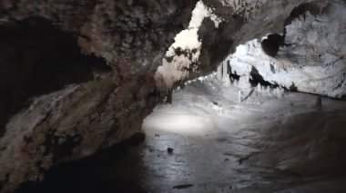 Karanlık bir mağarada muhteşem bir kaya oluşumu. Mağaranın tavanında kocaman sarkıtlar asılı..