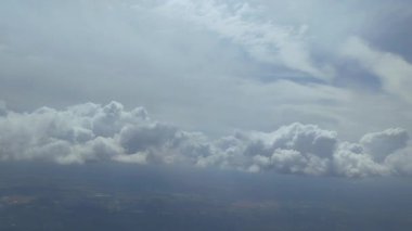 Gökyüzü bulutlarla kaplı, güneş onların arasından parlıyor. Uçaktan bak. Beyaz ve kabarık bulutlar barışçıl ve huzurlu bir atmosfer yaratır. Yüksek kalite