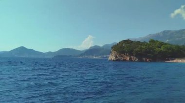 Kayalık bir kıyı şeridi olan güzel mavi bir okyanus. Gökyüzü açık ve güneş parlıyor. Yüksek kalite