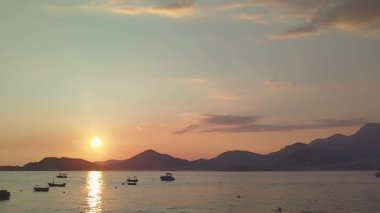 Güneş okyanusun üzerinde batıyor, suyun üzerine sıcak bir parıltı saçıyor. Gün batımında demirli teknelerle dolu bir deniz bölmesi tasasız ve sakin bir atmosfer yaratır. Yüksek kalite