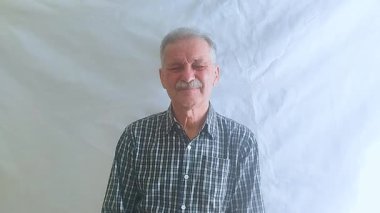 Hevesli bir ruh hali içinde yaşlı bir adam hayır der ve olumsuz bir şekilde başını sallar ve kameraya bakar. Beyaz arkaplanda bir portre.