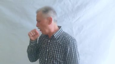 Kareli gömlekli yaşlı bir adam çok sert öksürüyor, midesi bulanıyor ve üşütüyor. Beyaz arkaplanda bir portre.