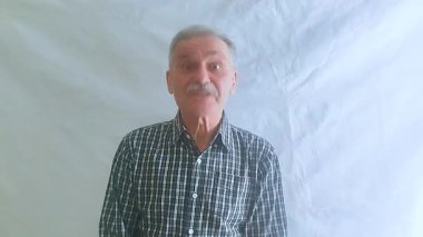 Hevesli bir ruh hali içinde yaşlı bir adam evet der, başını sallar ve kameraya bakar. Beyaz arkaplanda bir portre.