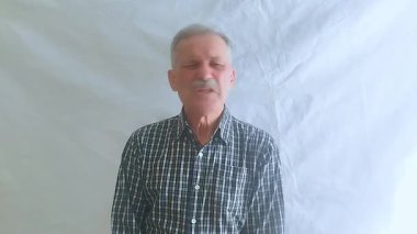 Hevesli bir ruh hali içinde yaşlı bir adam hayır der ve olumsuz bir şekilde başını sallar ve kameraya bakar. Beyaz arkaplanda bir portre.