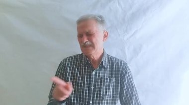 Hevesli bir ruh hali içinde yaşlı bir adam hayır der ve olumsuz bir şekilde başını sallar ve kameraya bakar. Beyaz arkaplanda bir portre.