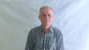 Hevesli bir ruh hali içinde yaşlı bir adam hayır der ve olumsuz bir şekilde başını sallar ve kameraya bakar. Beyaz arkaplanda bir portre.