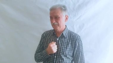 Kareli gömlekli yaşlı bir adam çok sert öksürüyor, midesi bulanıyor ve üşütüyor. Beyaz arkaplanda bir portre.