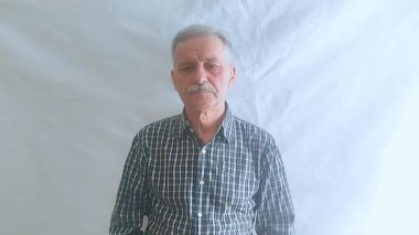 Kareli gömlekli yaşlı bir adam çok sert öksürüyor, midesi bulanıyor ve üşütüyor. Beyaz arkaplanda bir portre.