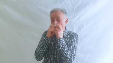 Kareli gömlekli yaşlı bir adam alerji yüzünden çok kötü hapşırır, kendini hasta hisseder ve nezle olur. Beyaz arkaplanda bir portre.