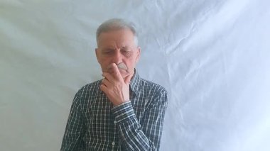 Kareli gömlekli yaşlı bir adam aktif olarak bir sorun düşünüyor ve doğru çözüm ona geliyor. Beyaz arkaplanda bir portre.