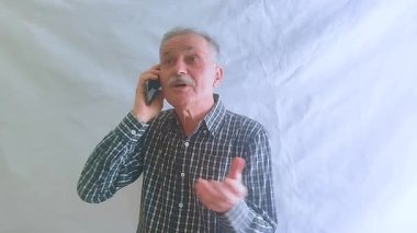 Kareli gömlekli yaşlı bir adam akıllı telefonuyla doktora danışıyor. Beyaz arkaplanda bir portre.