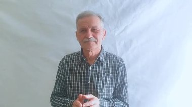 Kareli gömlekli yaşlı bir adam başarısız bir performansı alaycı bir şekilde alkışlıyor. Beyaz arkaplanda bir portre.