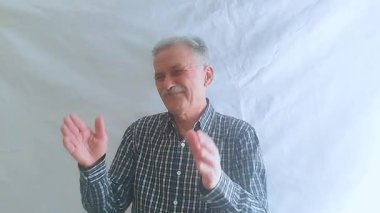 Kareli gömlekli yaşlı bir adam başarısız bir performansı alaycı bir şekilde alkışlıyor. Beyaz arkaplanda bir portre.