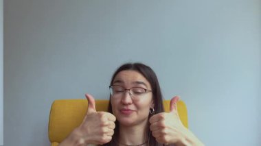 Genç ve çekici bir kız şaşırdı ve baş parmağını kaldırdı. Yüksek kalite 4K görüntü.