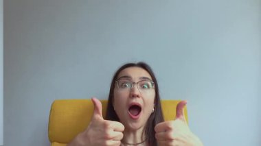 Genç ve çekici bir kız şaşırdı ve baş parmağını kaldırdı. Yüksek kalite 4K görüntü.