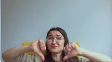 Genç ve çekici bir kız hayal kırıklığıyla baş parmağını kaldırıyor. Yüksek kalite 4k görüntü