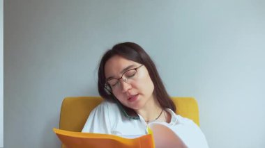 Genç ve çekici bir iş kadını telefonda konuşur ve belgelere bakar. Yüksek kaliteli FullHD görüntüler