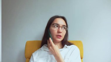 Genç ve çekici bir iş kadını telefonda konuşur ve belgelere bakar. Yüksek kaliteli FullHD görüntüler