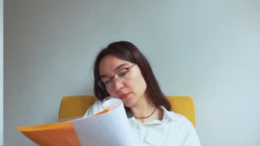 Genç ve çekici bir iş kadını telefonda konuşur ve belgelere bakar. Yüksek kaliteli FullHD görüntüler