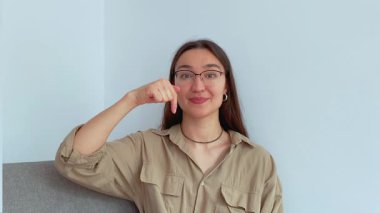 Genç ve çekici bir kız parmağını aşağı indirip onu bağlantıyı takip etmeye davet ediyor. Yüksek kalite 4k görüntü