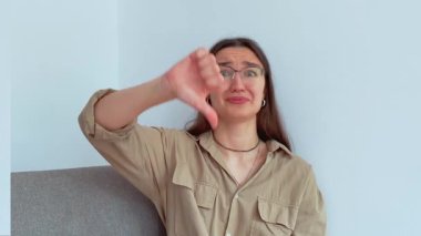 Genç ve çekici bir kız hayal kırıklığıyla baş parmağını kaldırıyor. Yüksek kalite 4k görüntü