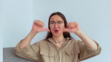 Genç ve çekici bir kız kafasını negatif bir şekilde sallar ve baş parmağını aşağı gösterir. Yüksek kalite 4k görüntü