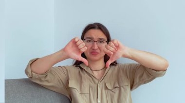 Genç ve çekici bir kız hayal kırıklığıyla baş parmağını kaldırıyor. Yüksek kalite 4k görüntü