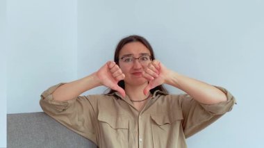 Genç ve çekici bir kız kafasını negatif bir şekilde sallar ve baş parmağını aşağı gösterir. Yüksek kalite 4k görüntü