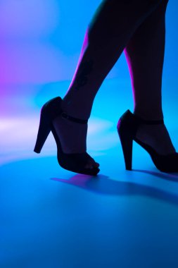 Seksi kıvrımlı bayanın bacakları ve yüksek topuklu topuklu ayakkabıları disko dans ışıklarında gece kulübünde..