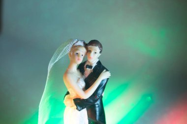 Düğün çifti pasta üstte plastik figürler smokin gece elbisesi, beyaz gelinlik peçesi.