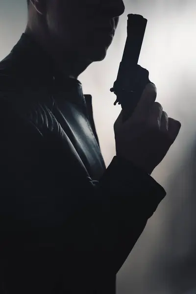 Detective spy thriller man with gun photo dark studio shot with cinematic lighting.