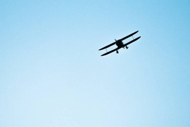 Mavi gökyüzünde uçan çift kanatlı uçak