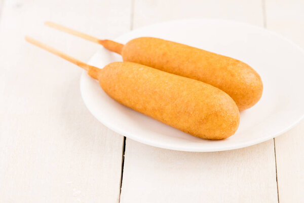 Два корн-дога на белой тарелке