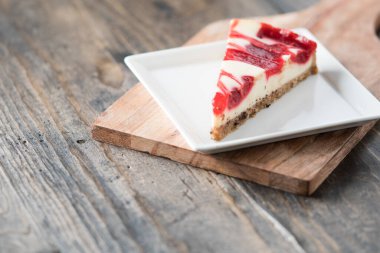 ahududu kıvrımlı cheesecake dilimi kare tabakta ahşap masa