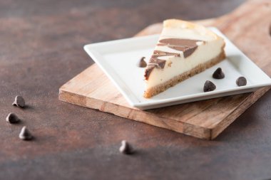 Kare tabakta çikolata kıvrımlı cheesecake dilimi