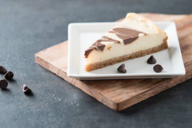 Kare tabakta koyu çikolata kıvrımlı cheesecake dilimi