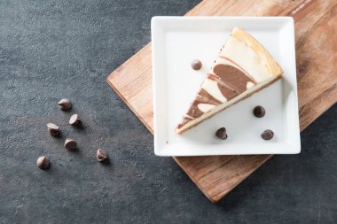 Kare tabakta çikolata kıvrımlı cheesecake dilimi. 