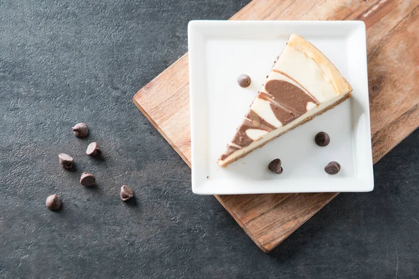 stock image Chocolate swirl cheesecake slice on square plate flat lay 