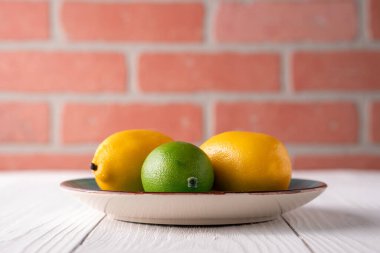 Eski beyaz çiftlik evindeki tabakta sahte limon meyvesi.