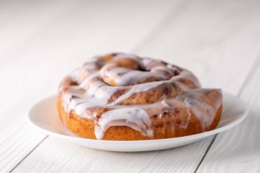 Beyaz çiftlik masasında büyük bir gurme kremalı tarçın rulosu.