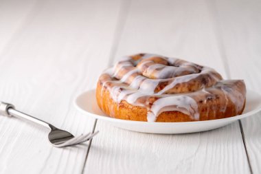 Beyaz çiftlik masasında büyük bir gurme kremalı tarçın rulosu.