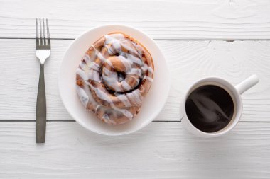 Beyaz çiftlik masasında büyük bir gurme kremalı tarçın rulosu.