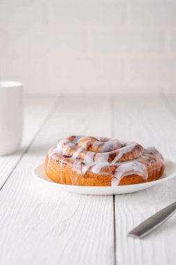 Beyaz çiftlik masasında büyük bir gurme kremalı tarçın rulosu.