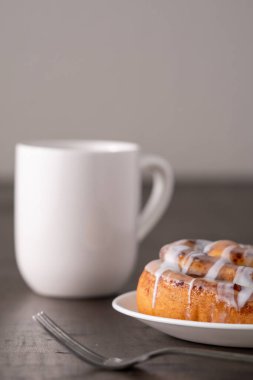 Kahverengi sıkıntılı masada büyük bir gurme kremalı tarçın rulosu.