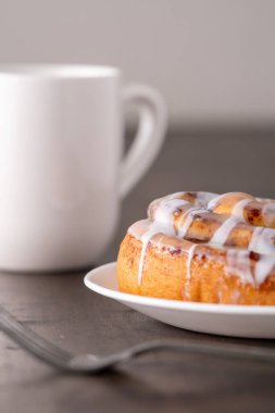 Kahverengi sıkıntılı masada büyük bir gurme kremalı tarçın rulosu.