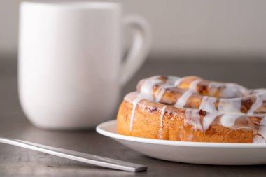 Kahverengi sıkıntılı masada büyük bir gurme kremalı tarçın rulosu.